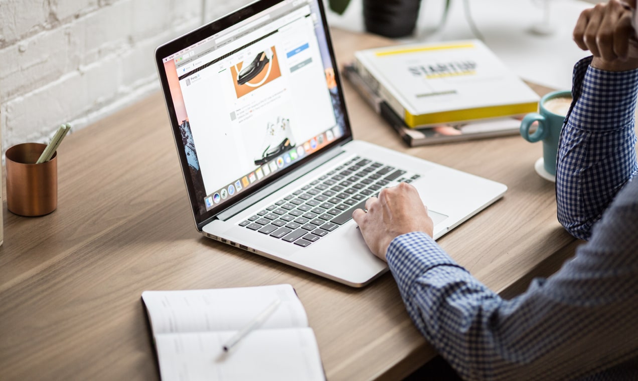 man using a laptop at a wooden desk