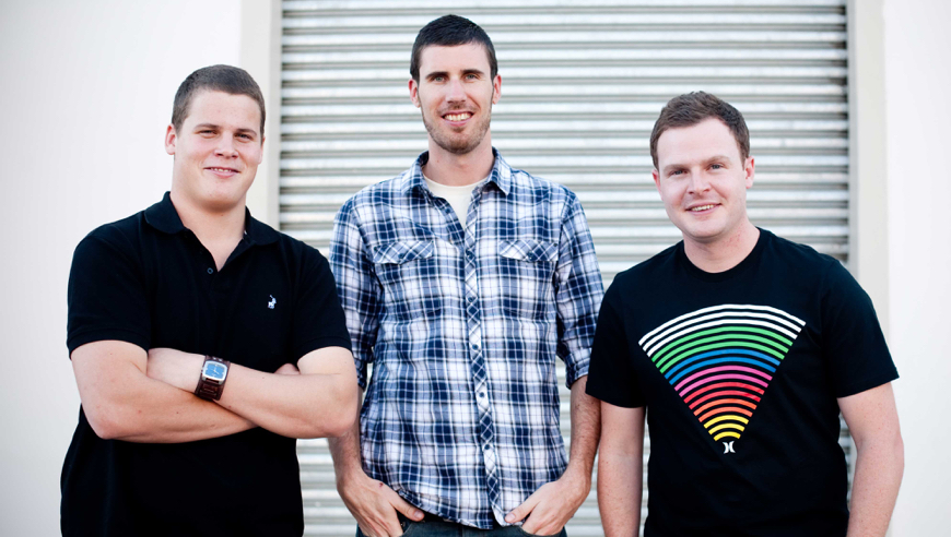 WooThemes co-founders Adii, Magnus, and Mark standing in from of a wall.