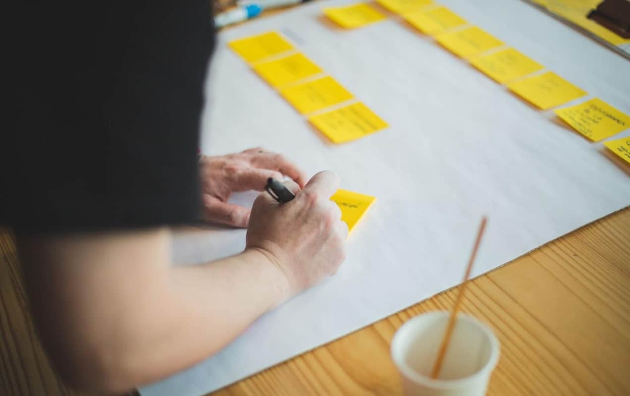 person writing on yellow sticky notes