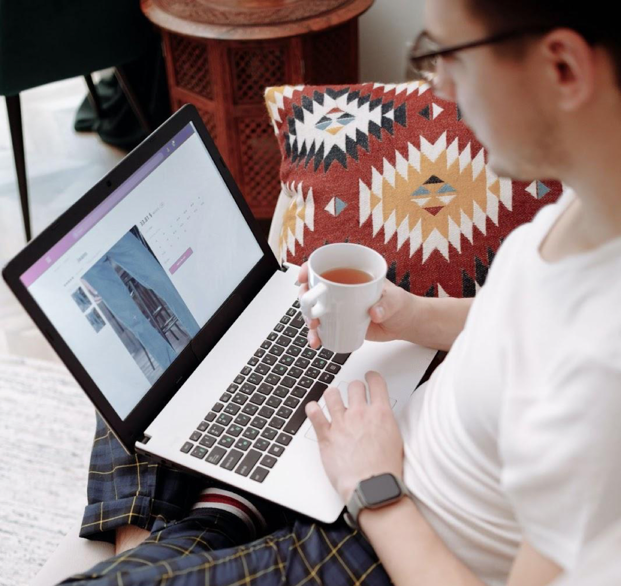 someone shopping on their laptop holding a cup of teae