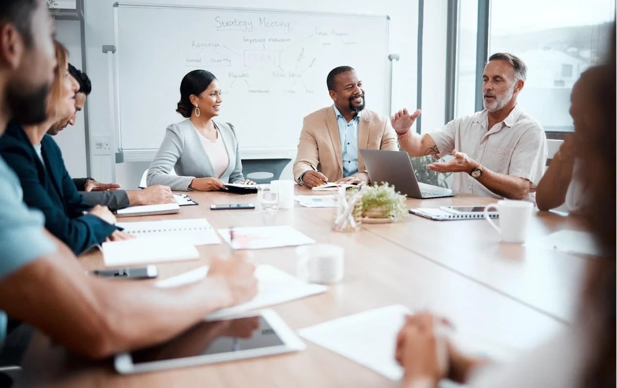 man describing something using his hands while sitting in a meeting room