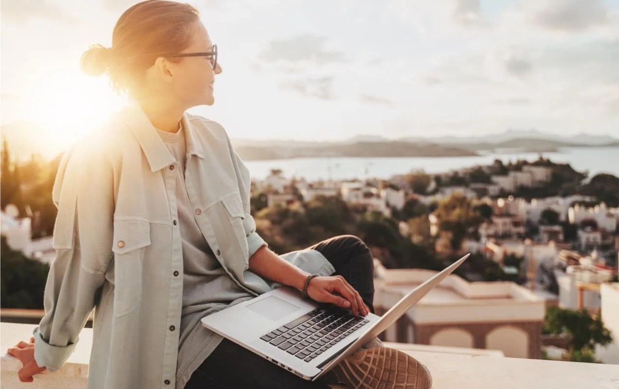 woman working on a laptop overlooking a city